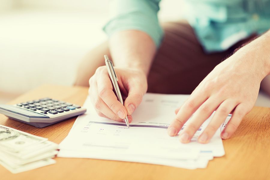 Ahorro, finanzas, economía y concepto de hogar - primer plano del hombre con la calculadora contando el dinero y haciendo notas en casa